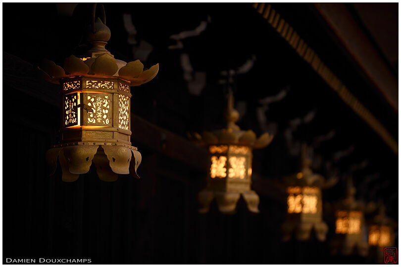 Row of golden lanterns at night, Kitano Tenmangu shrine, Kyoto, Japan