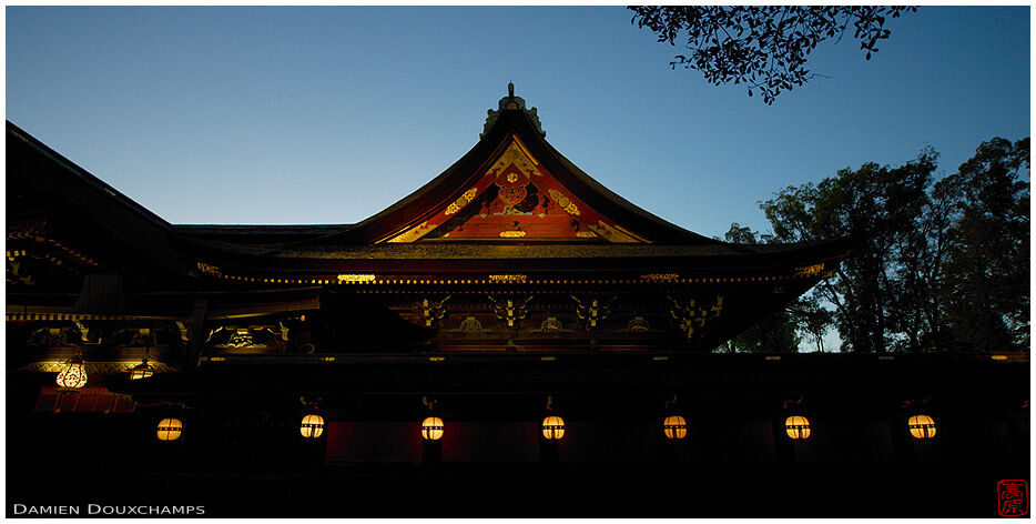 Glowing golden lanterns on Kitano Tenmangu shrine during early blue hour, Kyoto, Japan