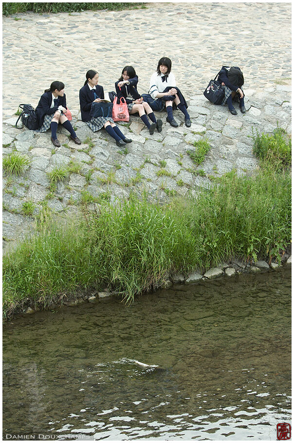 College girls resting along a river after class